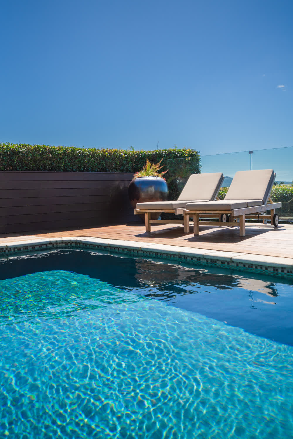 Tiled pool area with wooden decking and loungers